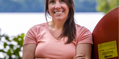 smiling woman leaning against a upside down canoe 
