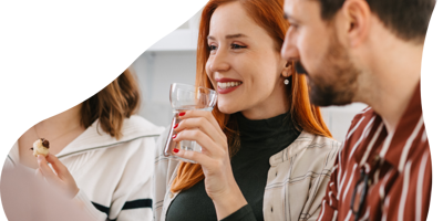 group of people around a table and one is drinking a glass of water